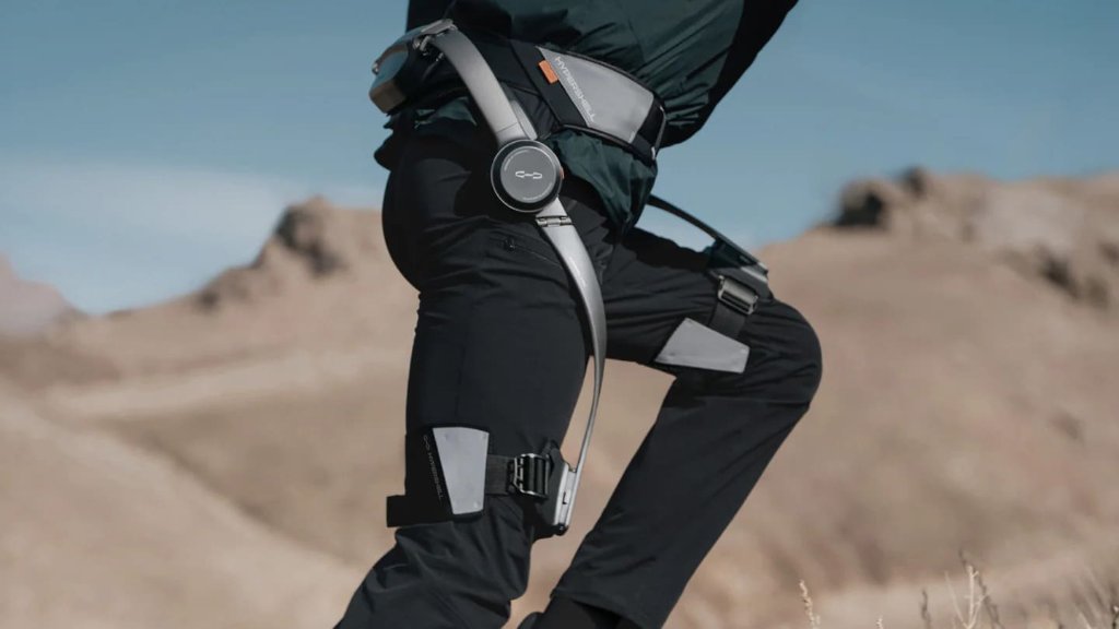 Randonneur équipé d'un exosquelette aux hanches, en montée sur un sentier de montagne